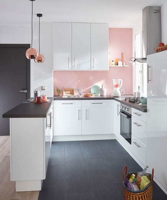 La petite cuisine est mise en valeur grâce à du mobilier blanc et gris et un pan de mur rose pâle qui adoucie et réchauffe l'ensemble. CP. Femme Actuelle