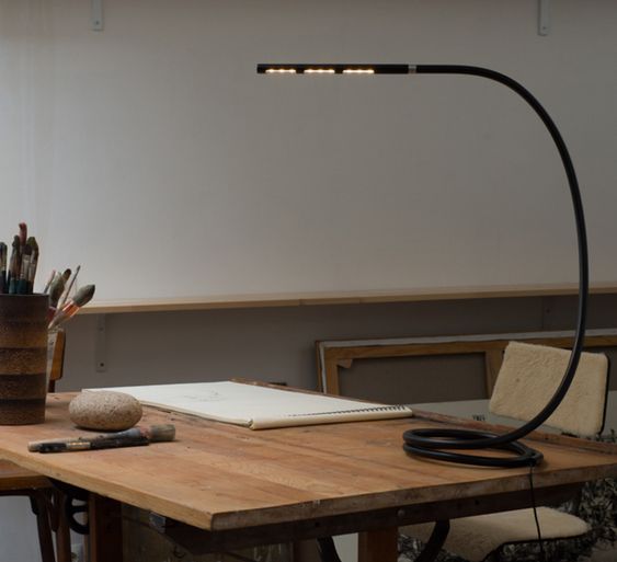 Une lampe de bureau noire avec des lignes très fines et design. Les ampoules donc plates et l'éclairage est léger. 